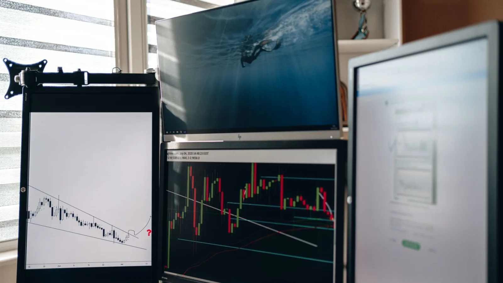 A home office setup featuring multiple monitors displaying trading charts and data analysis.