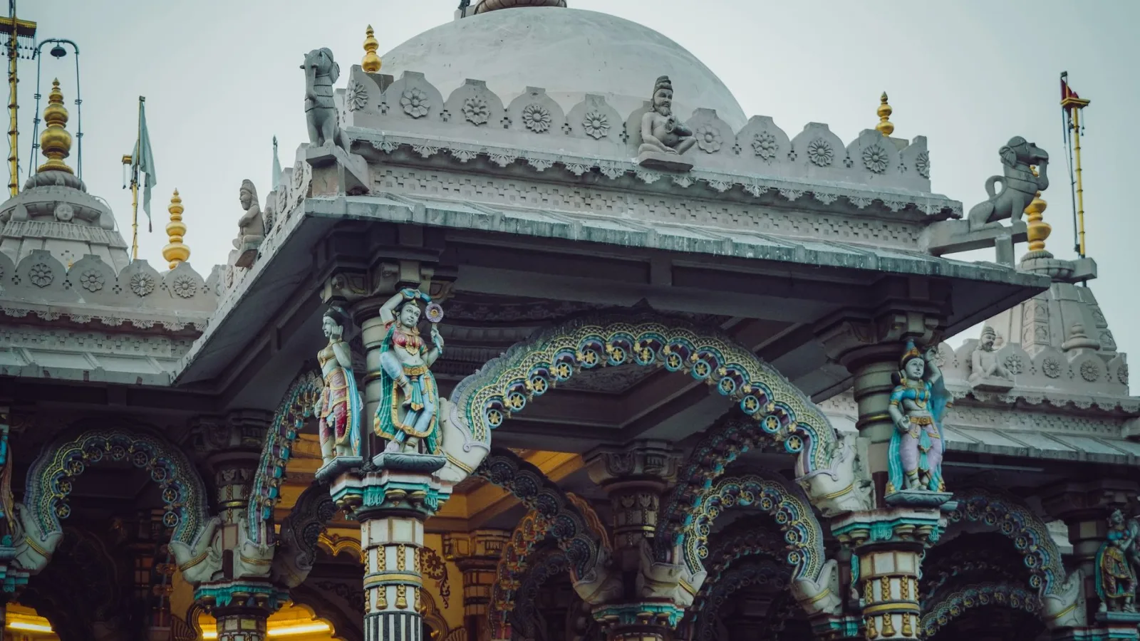 Intricate exterior of a Hindu temple showcasing colorful sculptures and detailed columns.