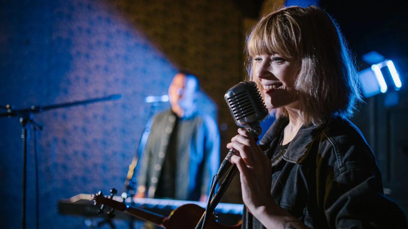 Smiling caucasian woman singing with vintage microphone during live music performance.