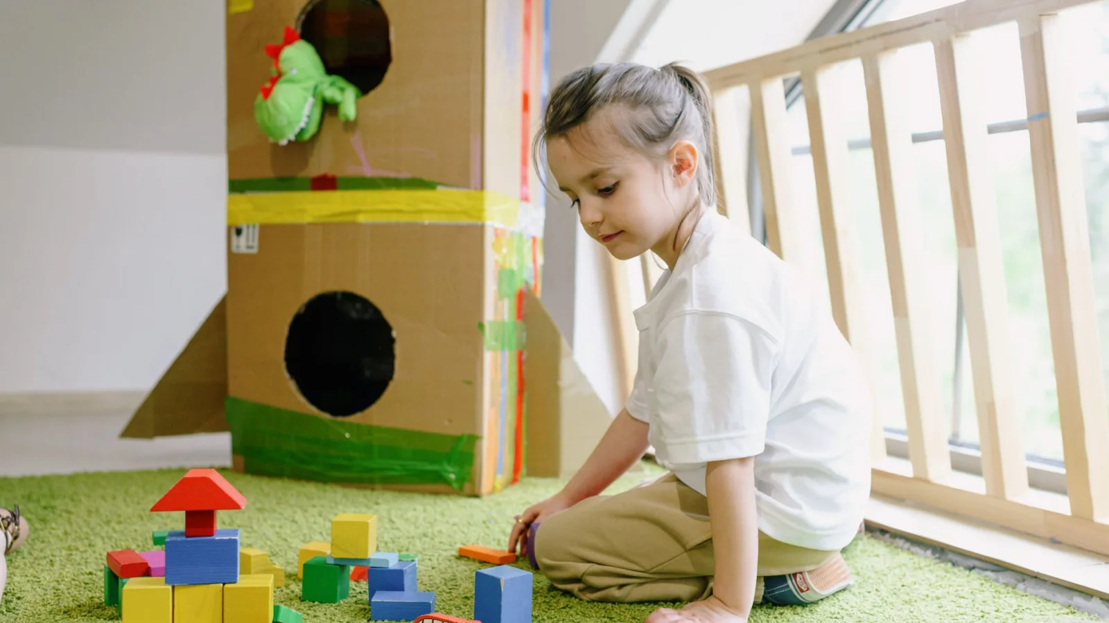 Young girl playing with colorful blocks in a bright indoor playroom.