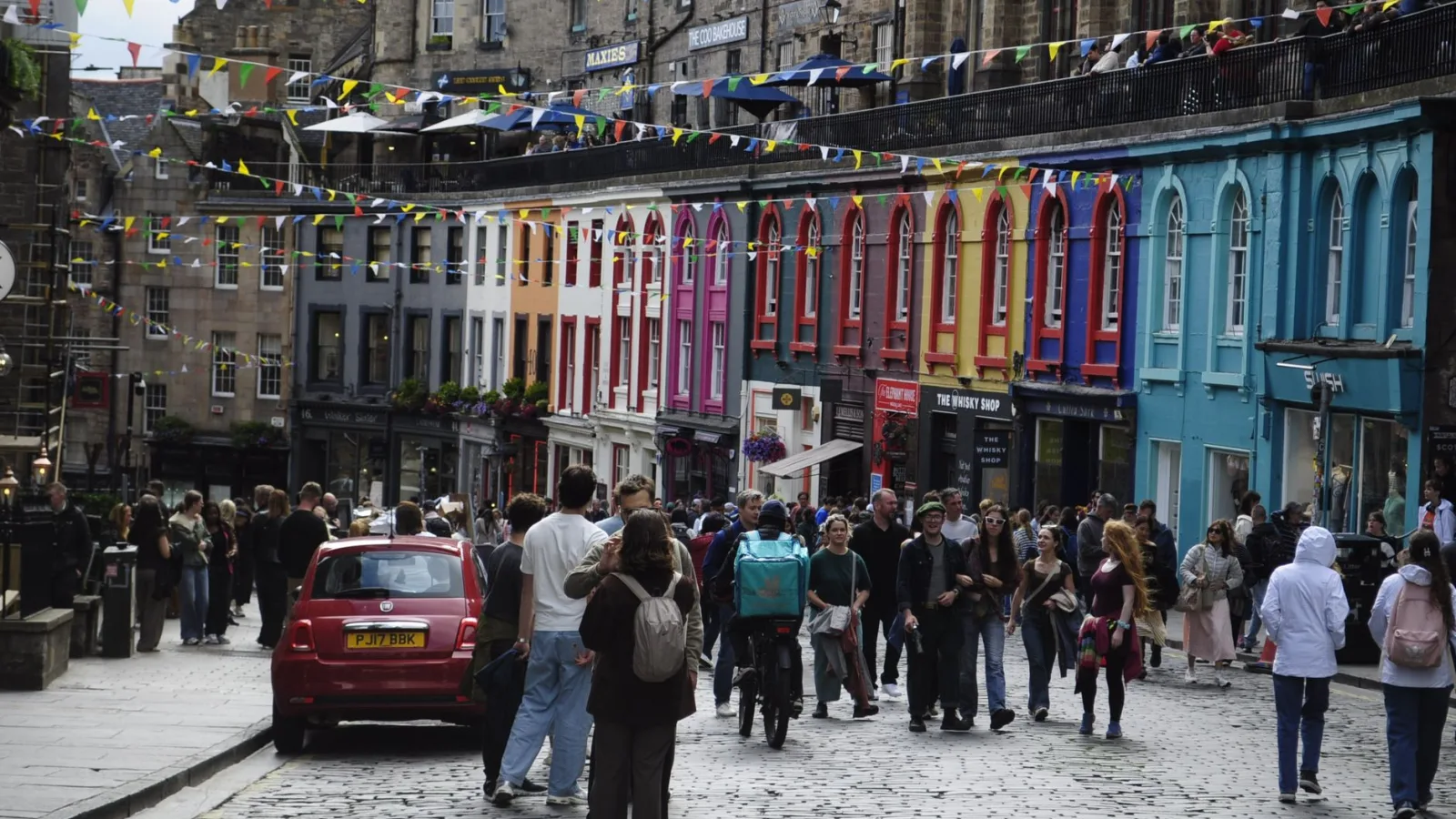 Vibrant scene on a busy Edinburgh street showcasing colorful buildings and lively crowd.