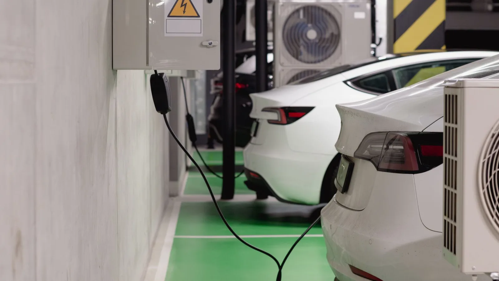 Electric vehicles charging at an indoor station in a modern underground garage.