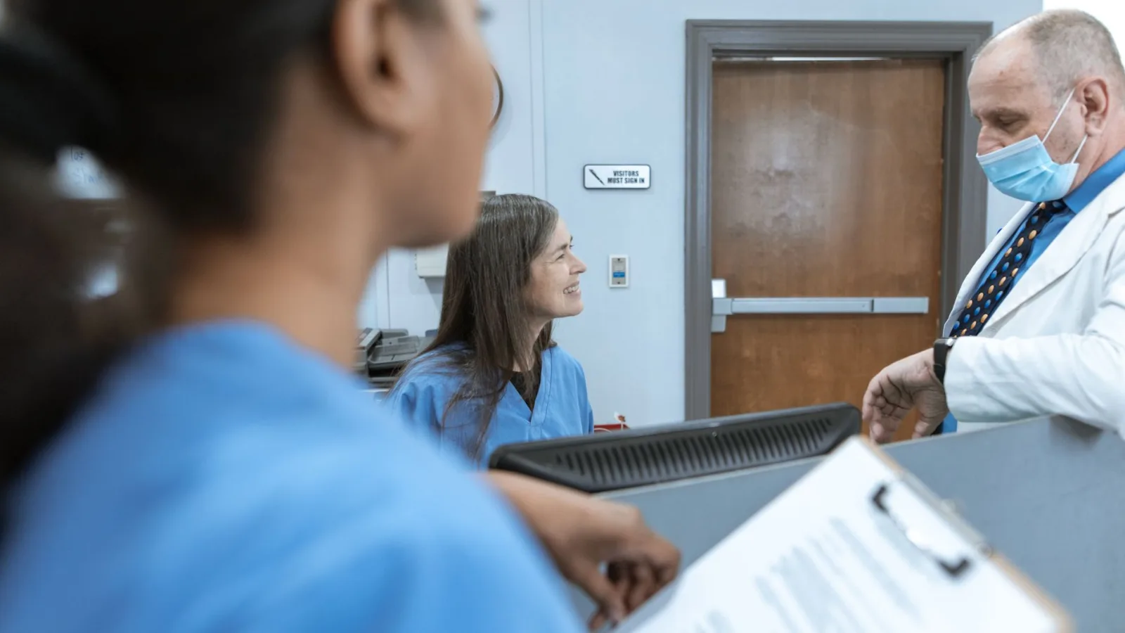 Healthcare professionals in discussion at a hospital reception, emphasizing teamwork and communication.