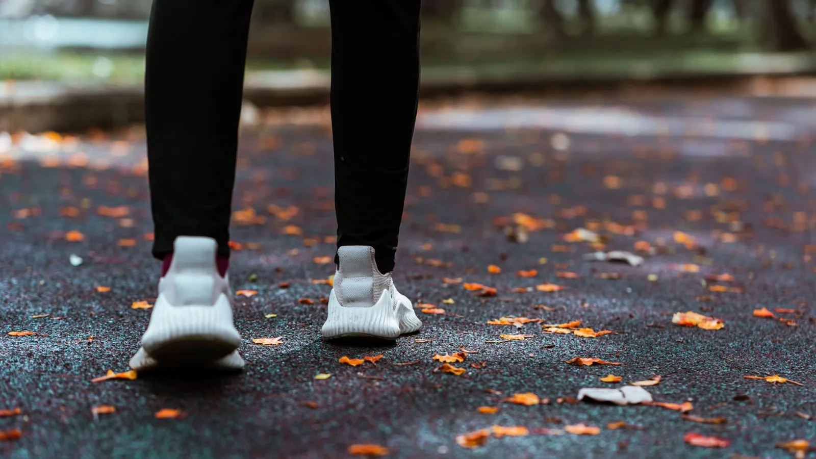 A person walking outdoors on a path while using a smartwatch