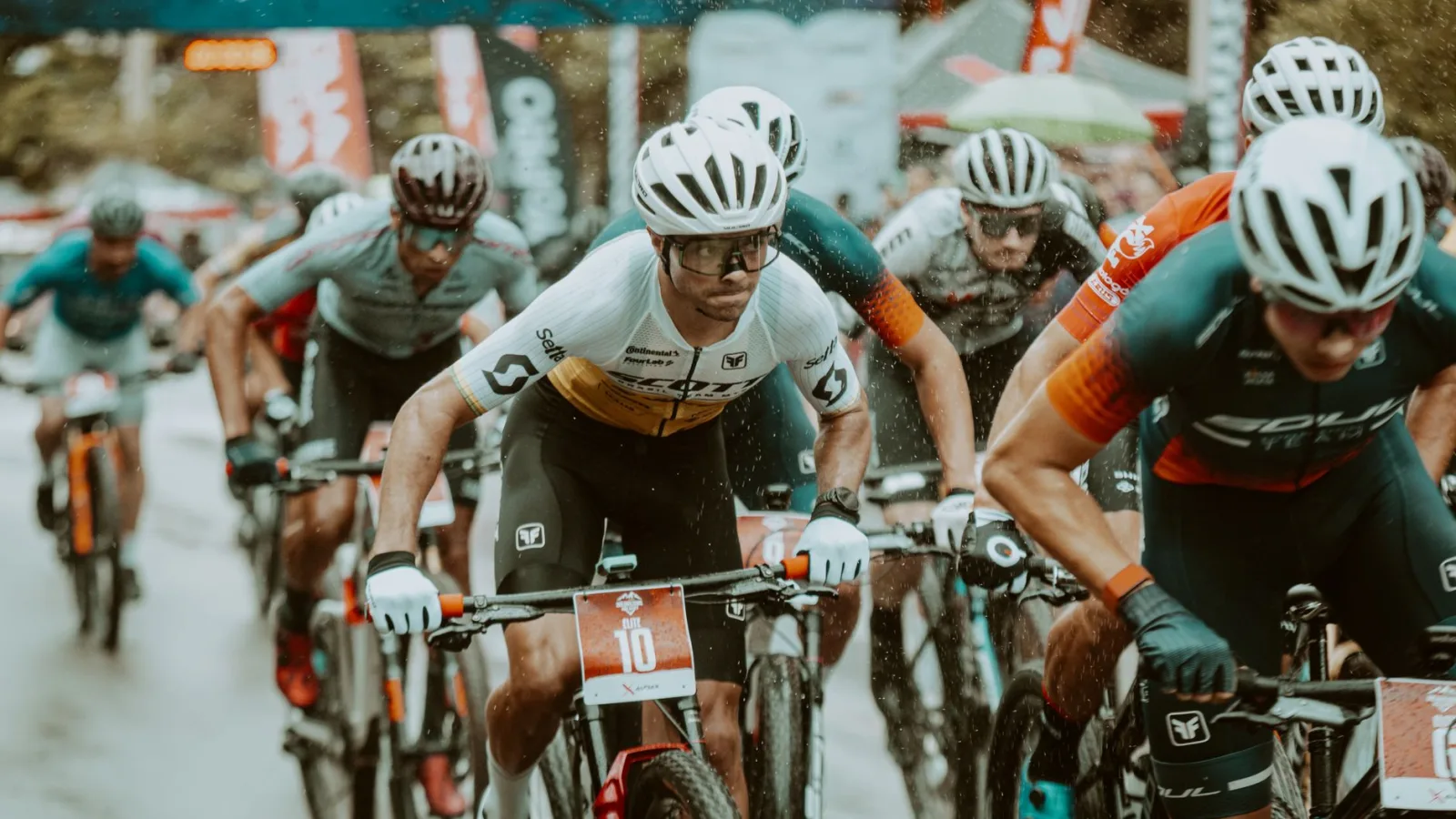 Competitive mountain bikers racing in the rain during an outdoor event, showcasing endurance and determination.