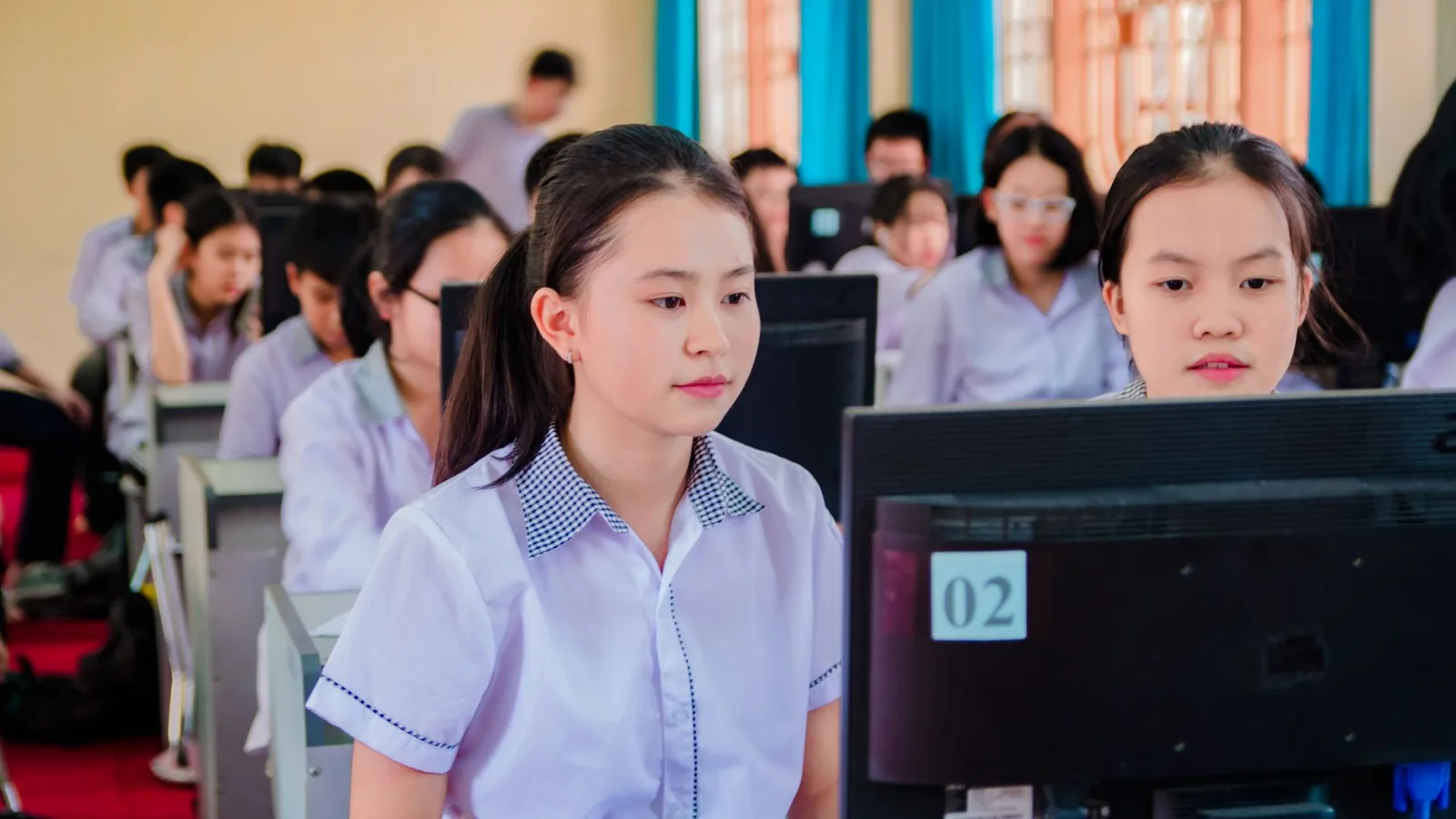 Group of high school students focused on learning in a computer lab setting.